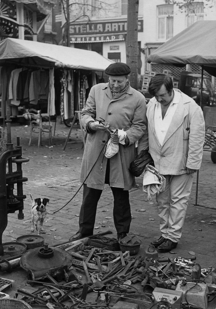Louis Van Lint inspecting a old tool at an open market.